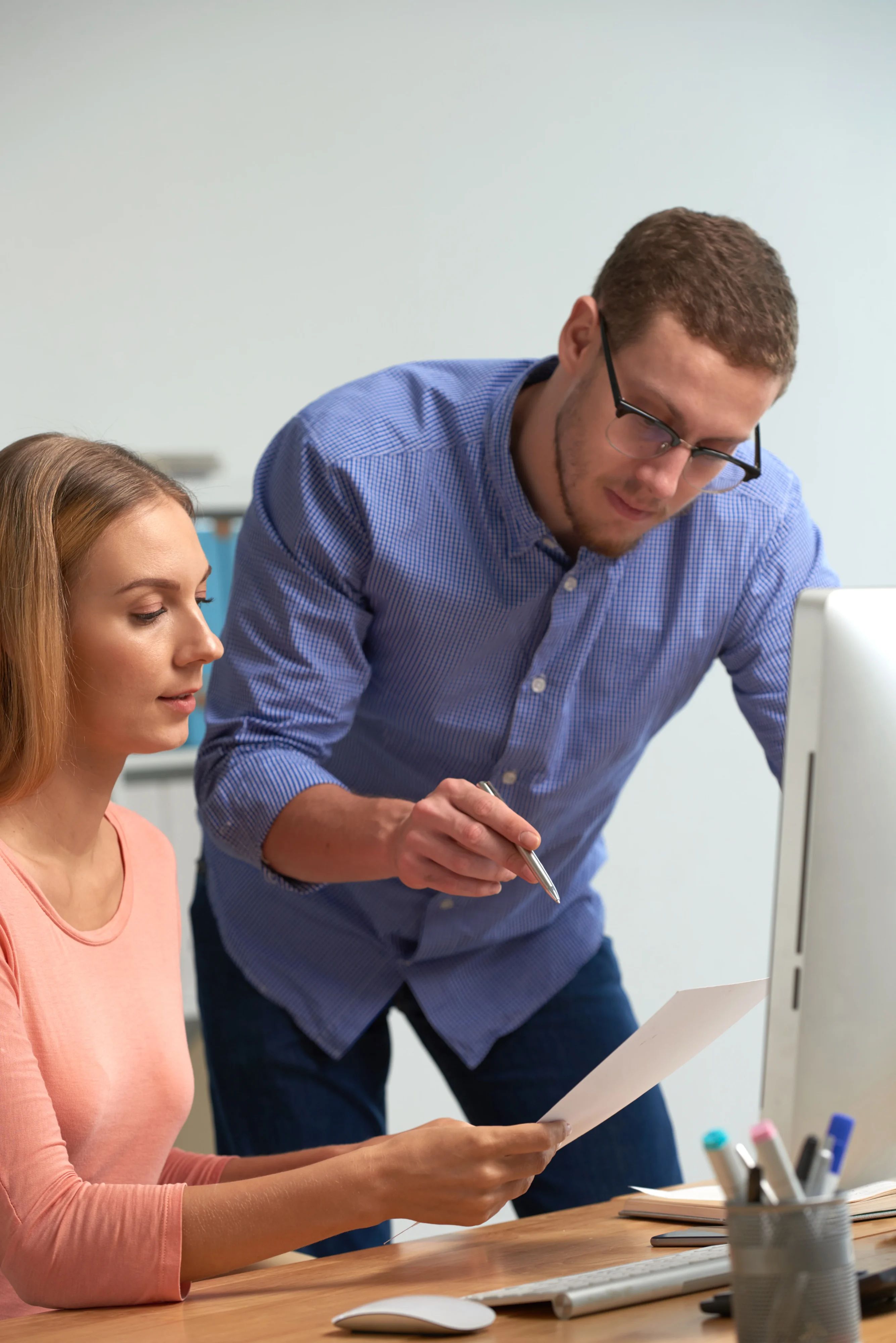 A designer and developer review a paper mockup against a computer screen to quickly iterate on a product feature.